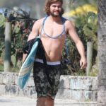Rafael Vitti caminha com prancha de surf pela Praia da Macumba, no Rio de Janeiro