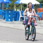 De bicicleta, Deborah Secco busca a filha na escola