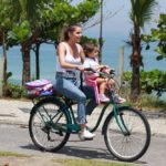 De bicicleta, Deborah Secco busca a filha na escola