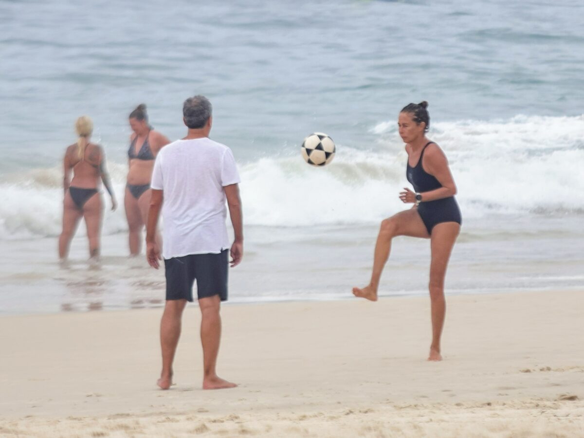 De maiô, atriz de ‘No Rancho Fundo’ pratica esportes na praia com o marido